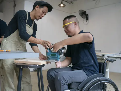 business manager helping new employee in wheelchair learn the job